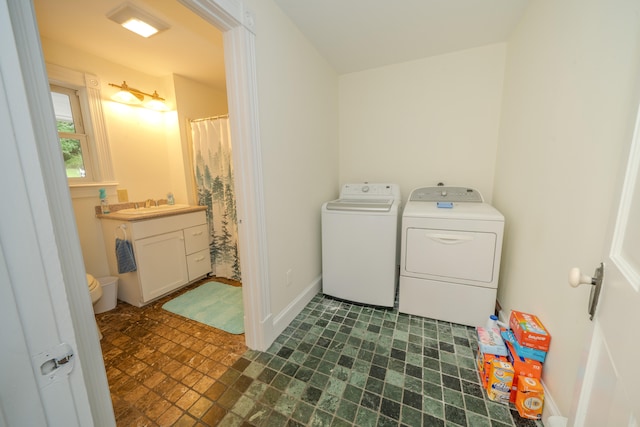 washroom with sink, washer and dryer, and dark tile patterned floors