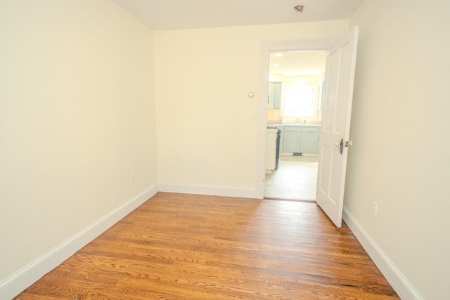 spare room with sink and light hardwood / wood-style flooring