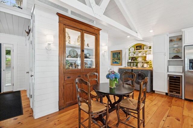 dining area with lofted ceiling with beams, washer / clothes dryer, wine cooler, and light hardwood / wood-style floors