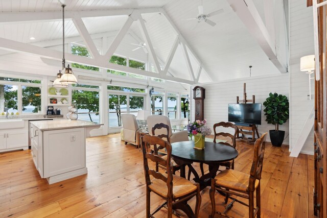 dining room featuring light wood-type flooring, ceiling fan, high vaulted ceiling, and beam ceiling