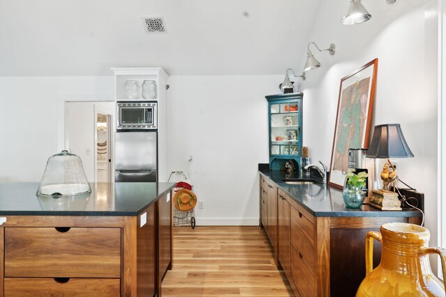 kitchen featuring kitchen peninsula, stainless steel appliances, sink, and light hardwood / wood-style floors