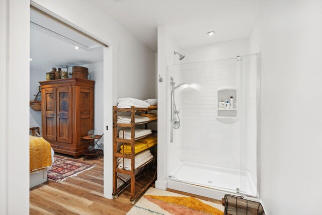 bathroom featuring wood-type flooring and a tile shower