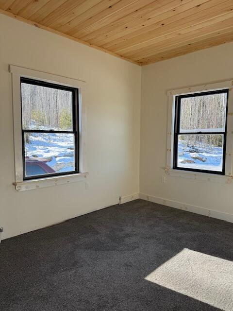 unfurnished room with wooden ceiling and dark carpet