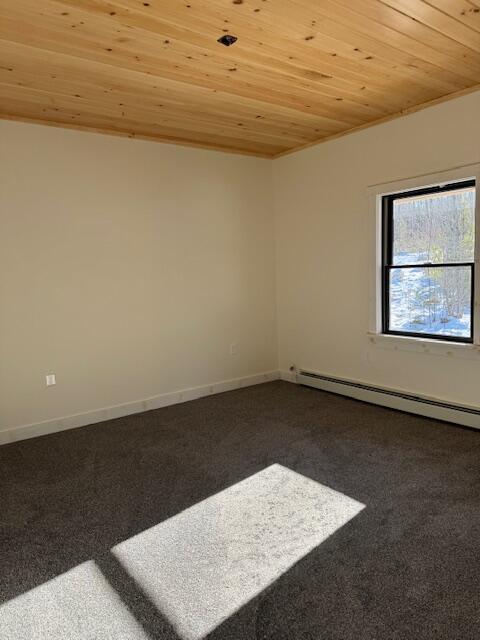 carpeted empty room featuring a baseboard heating unit and wooden ceiling