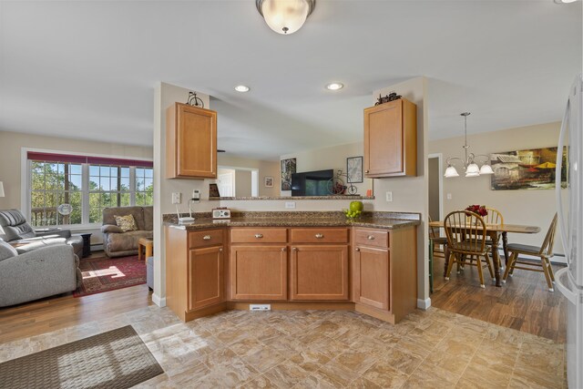 kitchen with light hardwood / wood-style flooring, kitchen peninsula, decorative light fixtures, and a chandelier