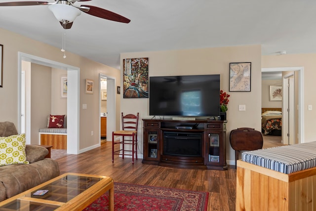 living room featuring a fireplace, ceiling fan, and dark hardwood / wood-style floors