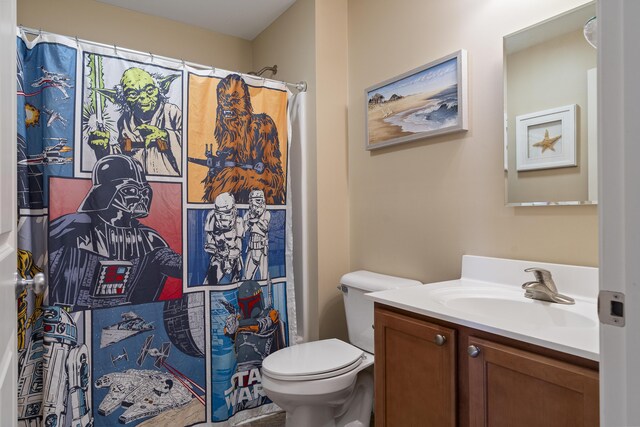 bathroom featuring walk in shower, toilet, and vanity