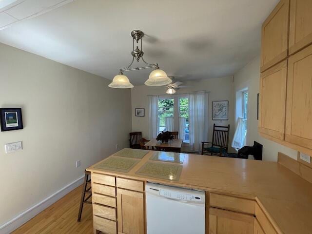 kitchen featuring dishwasher, light brown cabinetry, hanging light fixtures, and light hardwood / wood-style floors