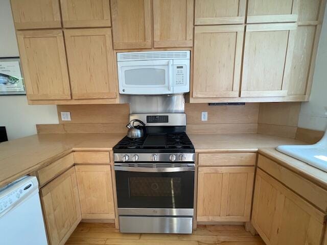 kitchen with light brown cabinets, white appliances, and light hardwood / wood-style floors