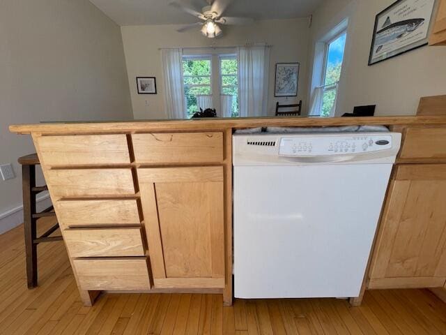 interior space featuring dishwasher, light brown cabinetry, light hardwood / wood-style floors, a kitchen bar, and ceiling fan