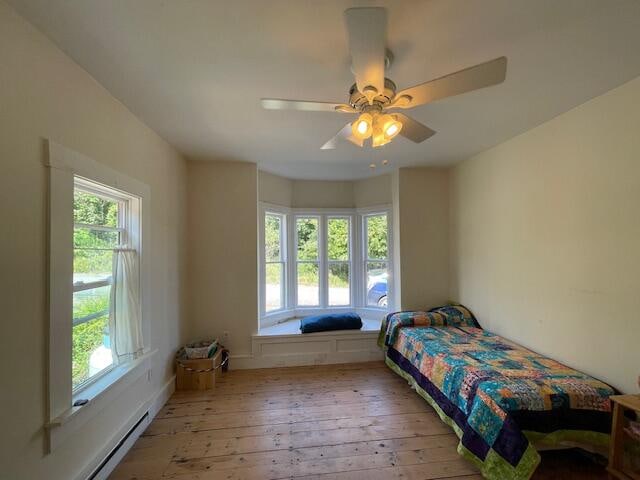 bedroom featuring light hardwood / wood-style flooring, a baseboard radiator, and ceiling fan