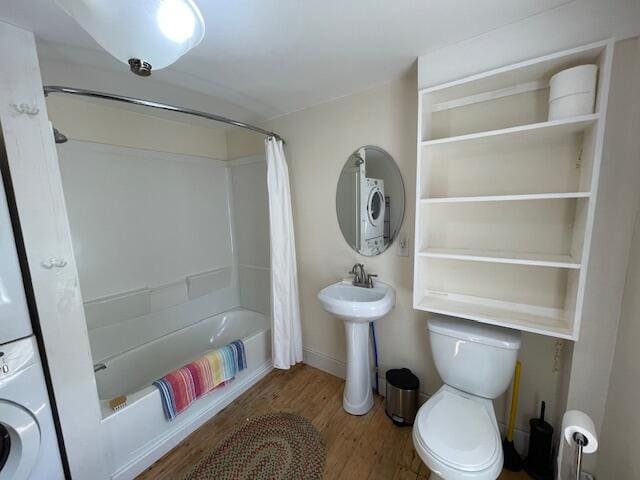 full bathroom featuring toilet, hardwood / wood-style floors, stacked washer / drying machine, sink, and shower / bath combo