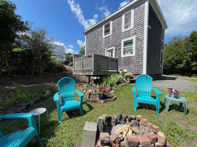 back of property with an outdoor fire pit and a deck