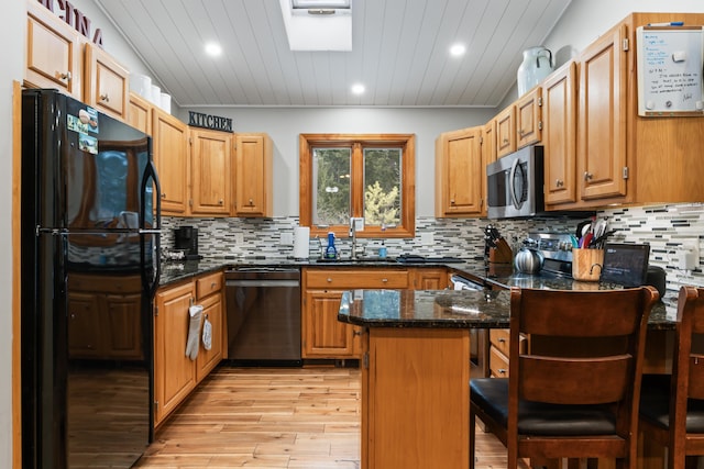 kitchen featuring sink, stainless steel appliances, a kitchen breakfast bar, a center island, and dark stone counters