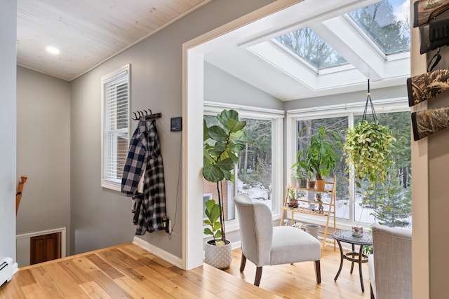 interior space with hardwood / wood-style flooring, lofted ceiling with skylight, and a baseboard heating unit