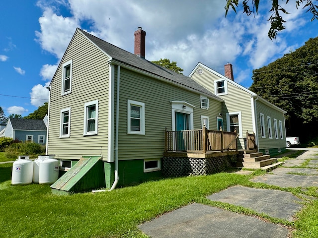 back of property with a yard and a wooden deck