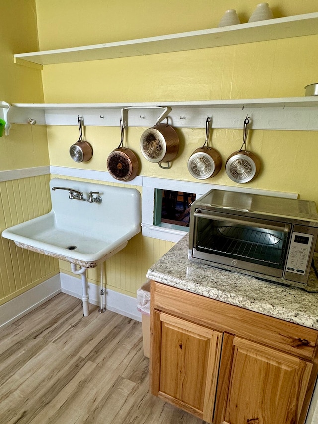 interior space featuring light wood-type flooring, light stone counters, and sink