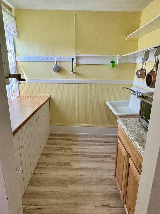 kitchen featuring light hardwood / wood-style flooring, wood walls, and sink