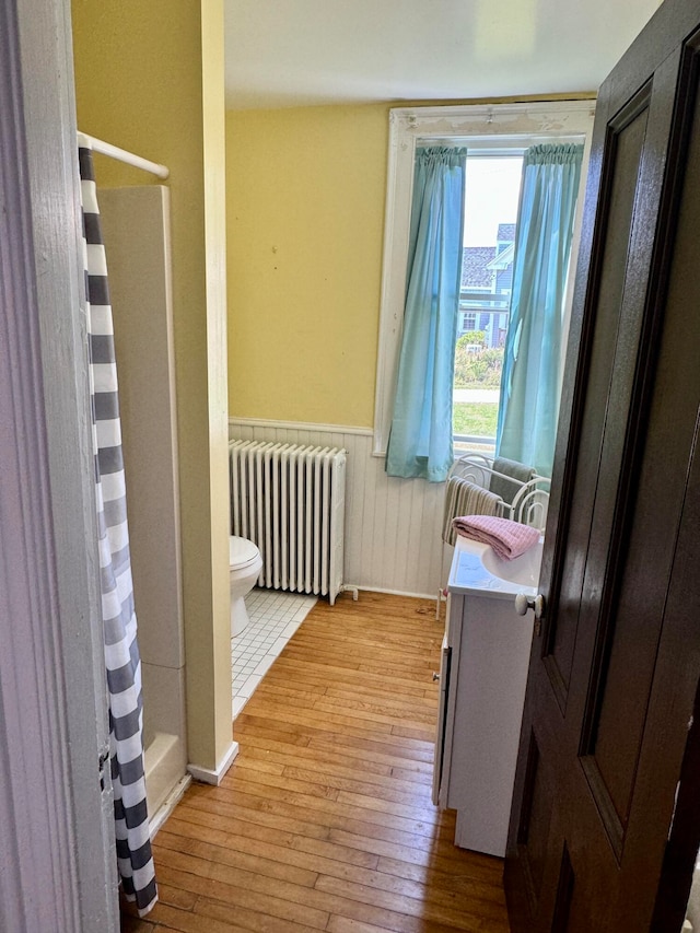 bathroom with vanity, radiator, hardwood / wood-style floors, toilet, and a shower with curtain