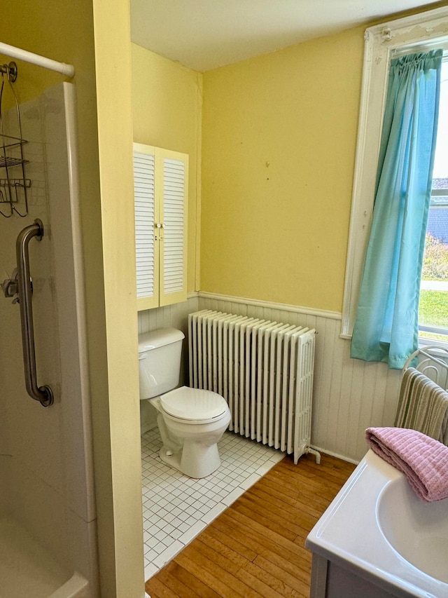 bathroom featuring vanity, a shower with shower door, radiator, toilet, and tile patterned floors