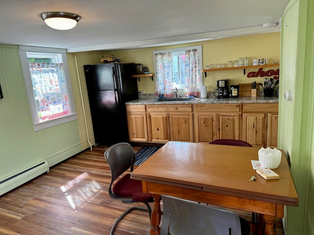 interior space featuring wood walls, light hardwood / wood-style flooring, sink, light stone counters, and black fridge