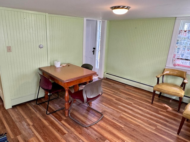 dining space featuring dark hardwood / wood-style flooring, baseboard heating, and wooden walls