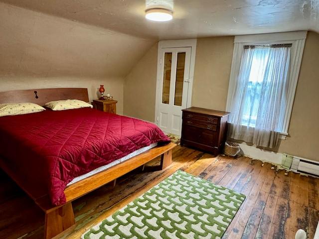 bedroom featuring light wood-type flooring, lofted ceiling, and a baseboard heating unit