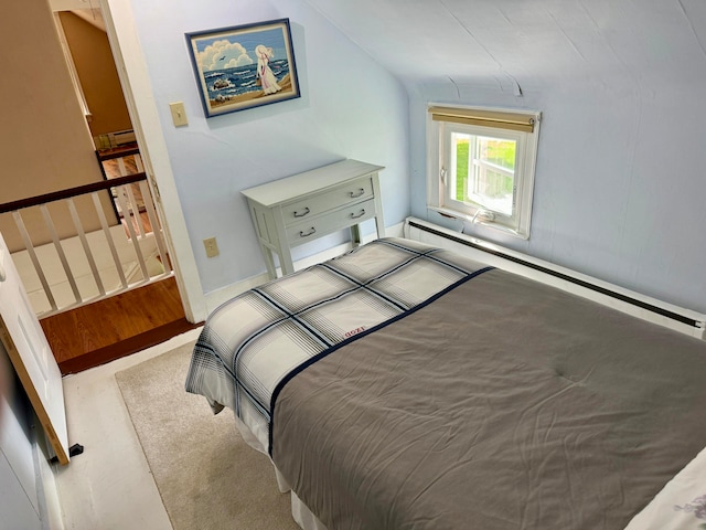 bedroom featuring a baseboard radiator, vaulted ceiling, and light carpet