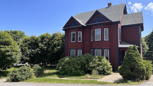 view of home's exterior featuring a chimney and roof with shingles