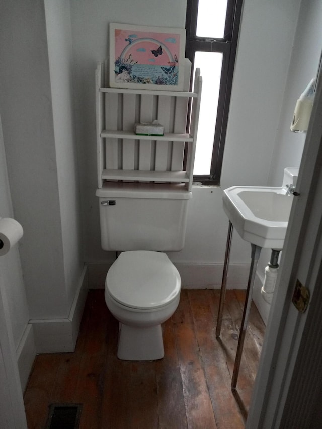 half bathroom featuring visible vents, baseboards, hardwood / wood-style floors, and toilet