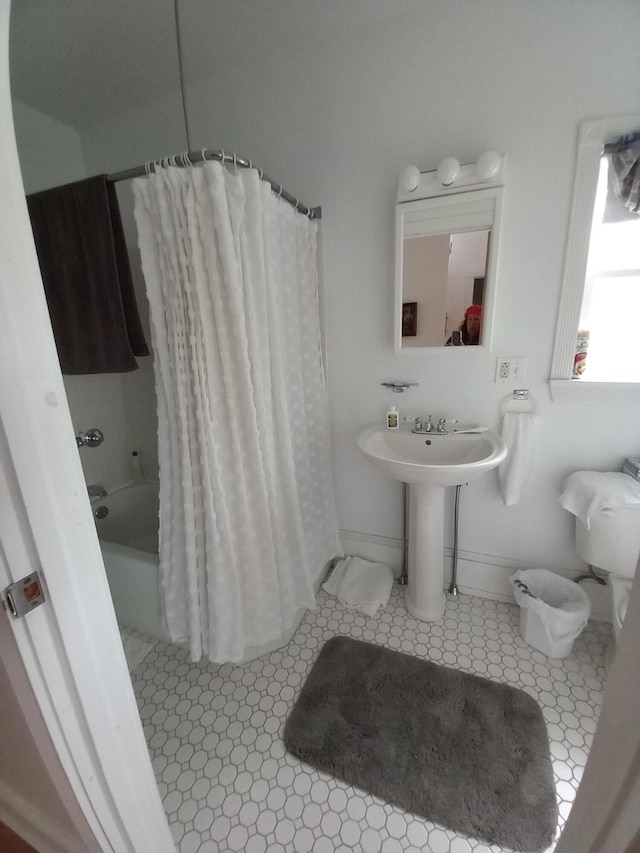 full bath featuring shower / bathtub combination with curtain, baseboards, a sink, and tile patterned floors