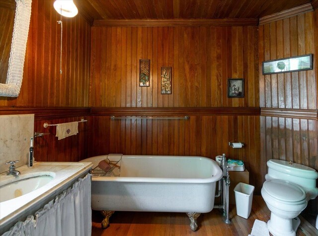 bathroom with wood ceiling, toilet, a bath, wood walls, and vanity