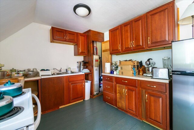 kitchen with water heater, stainless steel fridge, stove, sink, and dark wood-type flooring