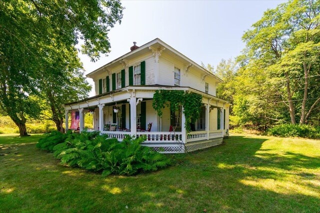 rear view of property featuring a yard and covered porch