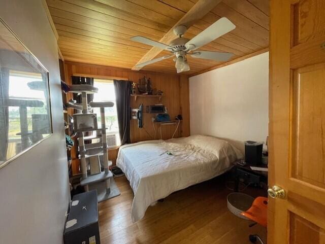 bedroom with wood ceiling, hardwood / wood-style floors, wood walls, and ceiling fan