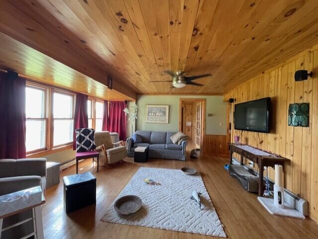 living room with wood ceiling, ceiling fan, wood walls, and hardwood / wood-style flooring