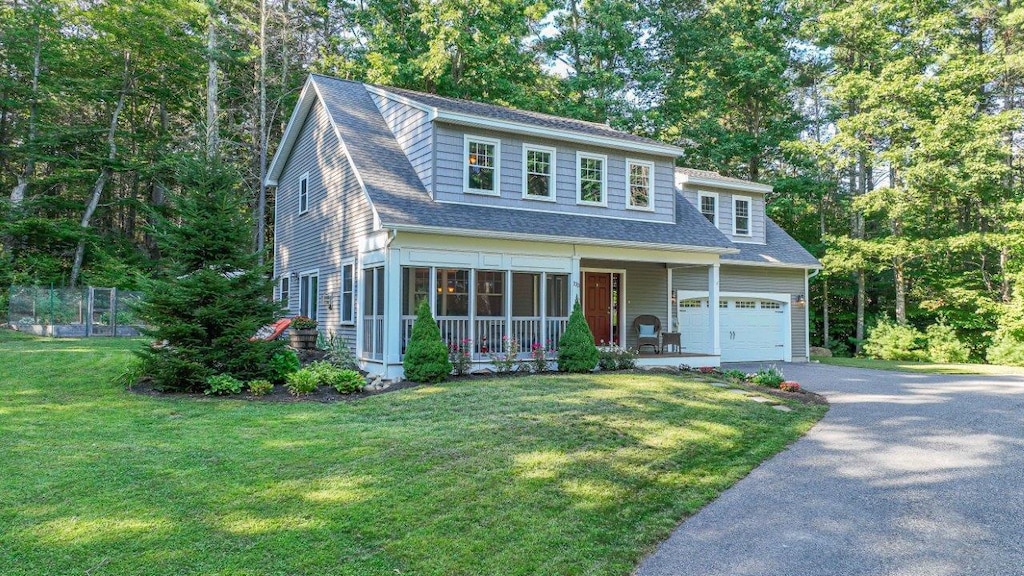 view of front of home with a garage, covered porch, roof with shingles, a front yard, and driveway