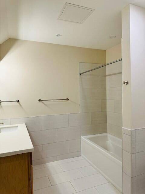 bathroom with tile patterned floors, tile walls, tiled shower / bath, and vanity