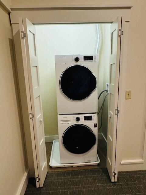 clothes washing area with stacked washer / dryer and dark tile patterned floors