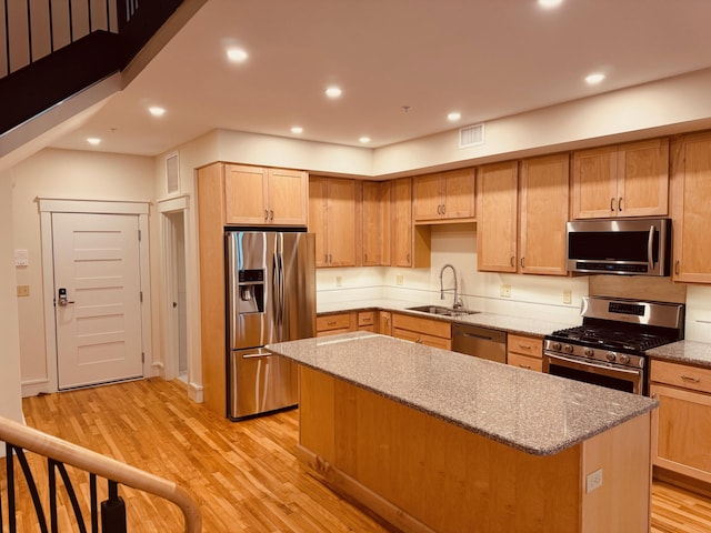 kitchen with light hardwood / wood-style flooring, a kitchen island, stainless steel appliances, and sink