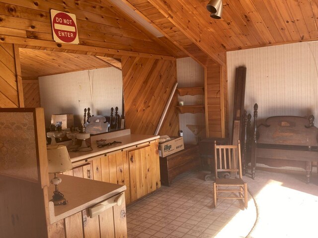 kitchen featuring lofted ceiling, light tile patterned floors, wooden walls, and wooden ceiling