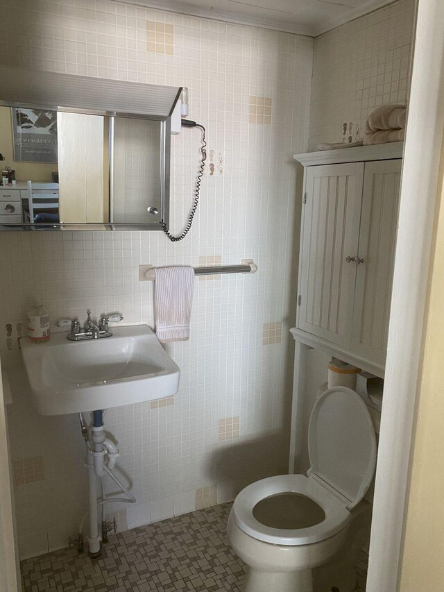 bathroom featuring toilet, tile patterned flooring, backsplash, sink, and tile walls