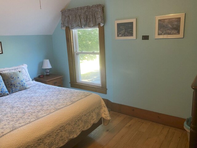 bedroom with vaulted ceiling and hardwood / wood-style flooring