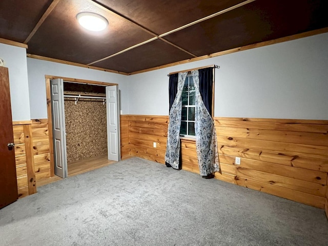 unfurnished bedroom with a closet, wood walls, and carpet floors