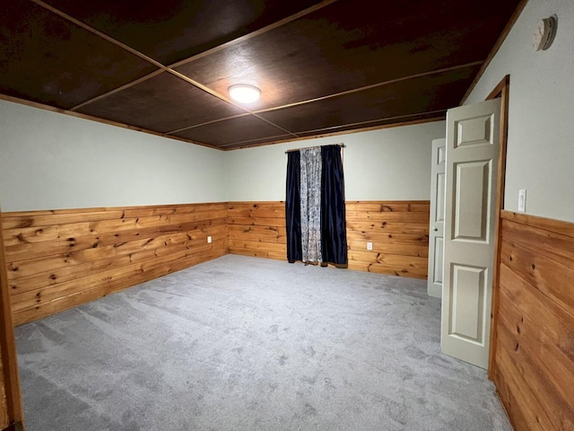 carpeted empty room featuring wooden walls