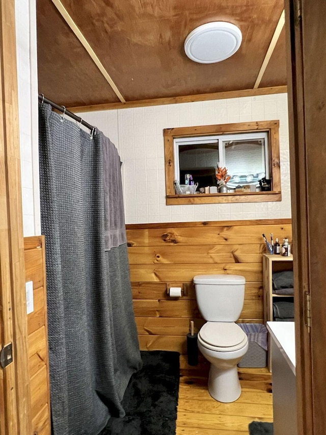 bathroom with vanity, toilet, hardwood / wood-style floors, and wooden walls