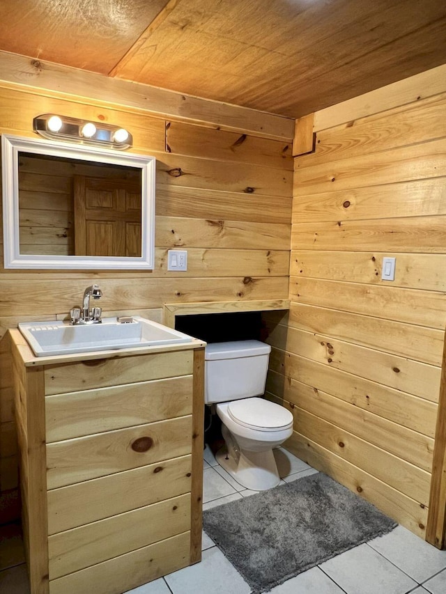 bathroom featuring tile patterned flooring, vanity, toilet, and wooden walls