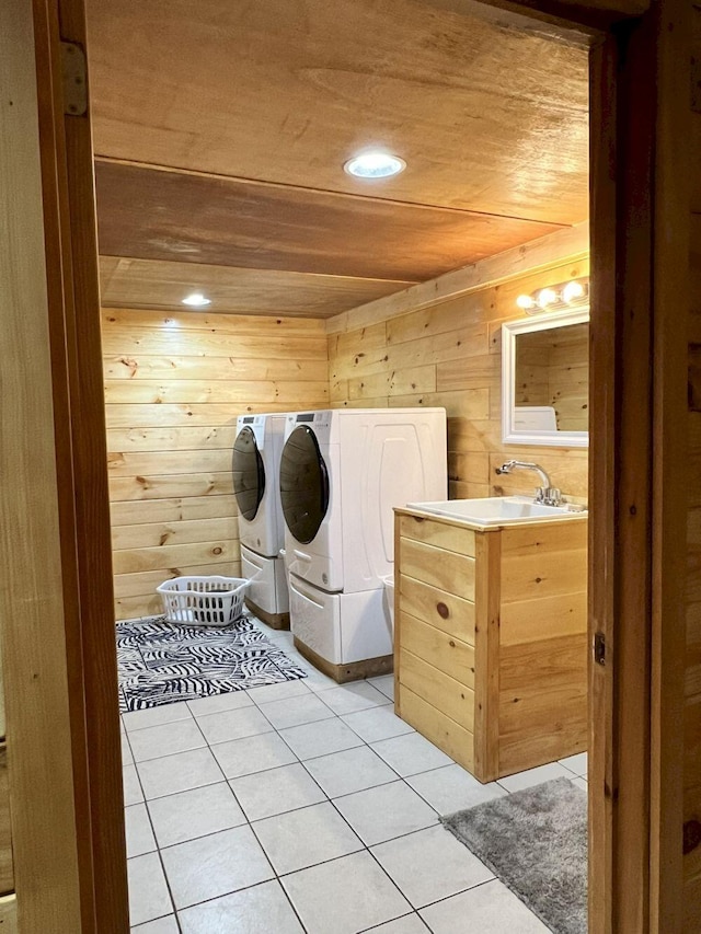 clothes washing area with wooden ceiling, light tile patterned flooring, washing machine and dryer, and wooden walls