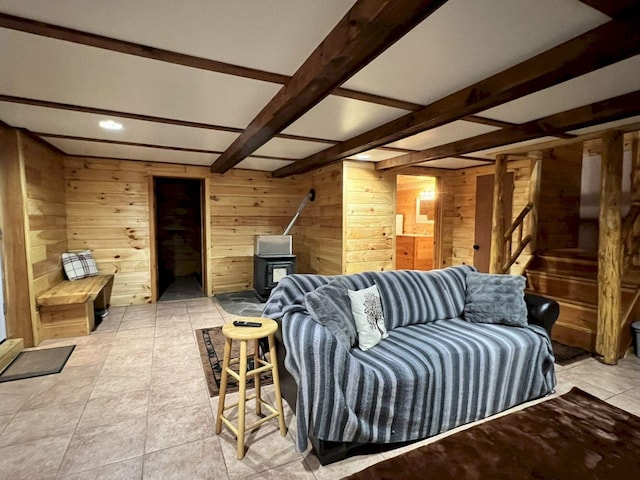 living room with wood walls, beam ceiling, and a wood stove