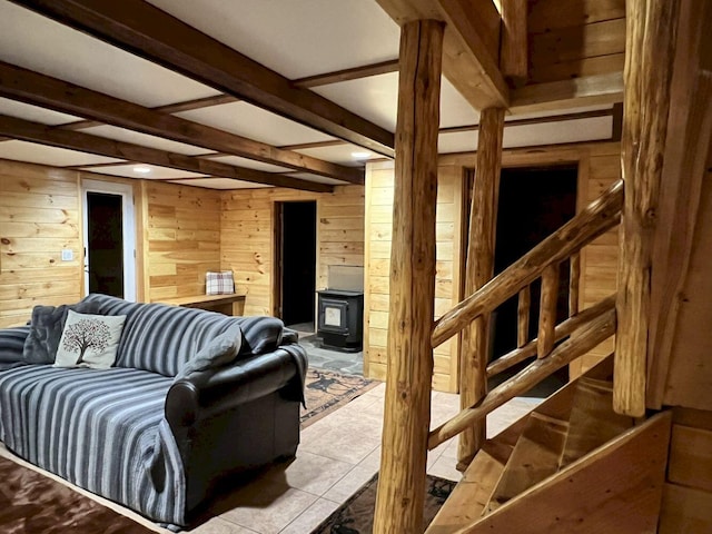 interior space featuring beamed ceiling, light tile patterned floors, a wood stove, and wooden walls